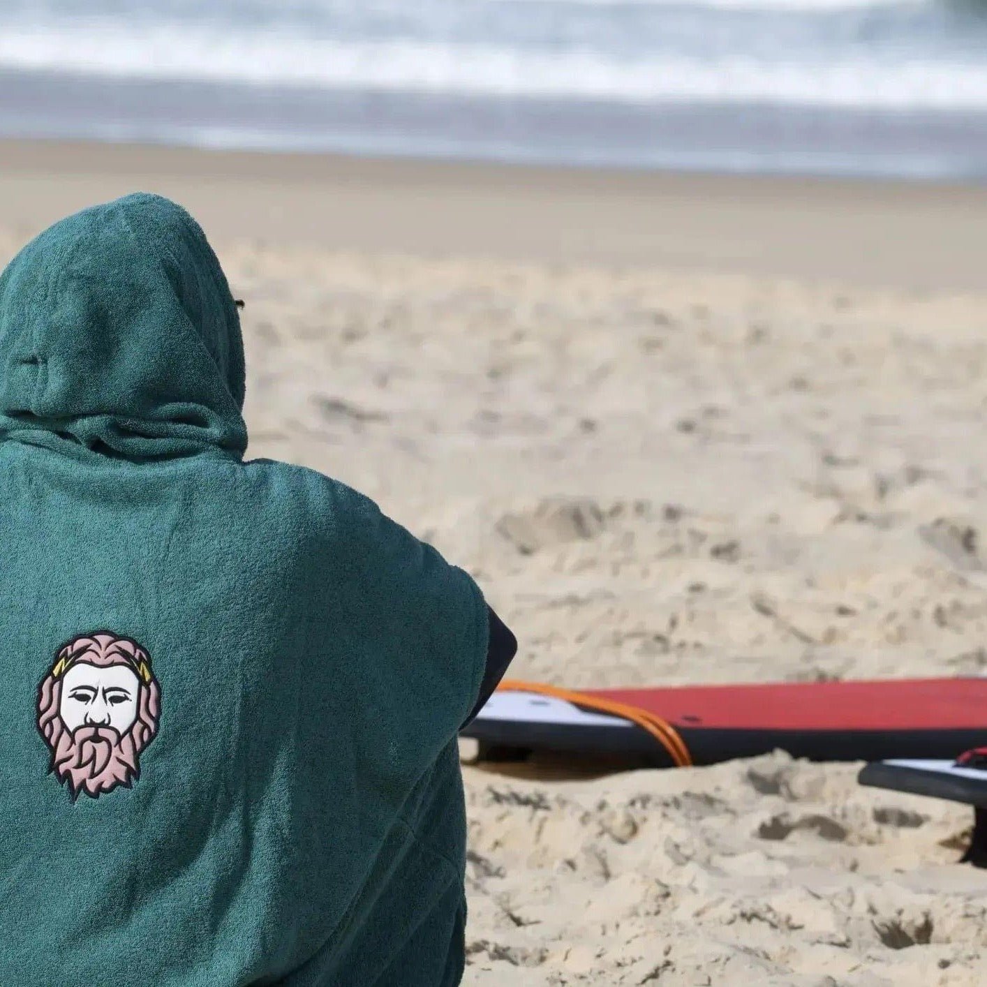 a person sitting on a beach next to a surfboard