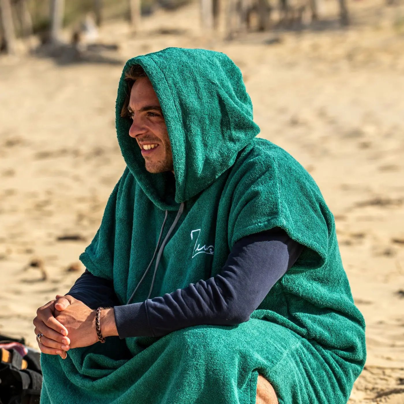 a man in a green towel sitting on the beach