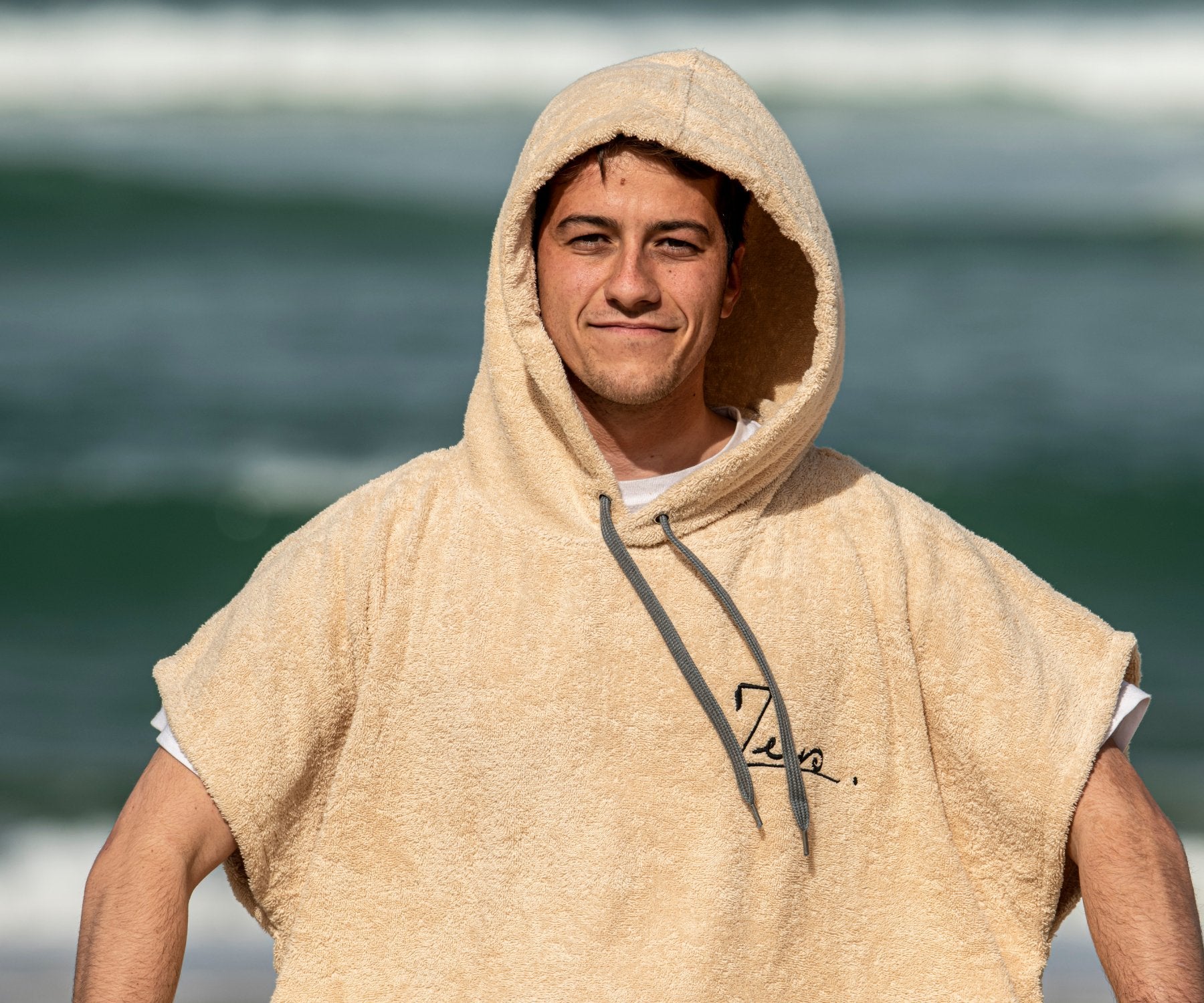 un surfeur souriant dans un poncho surf en coton 