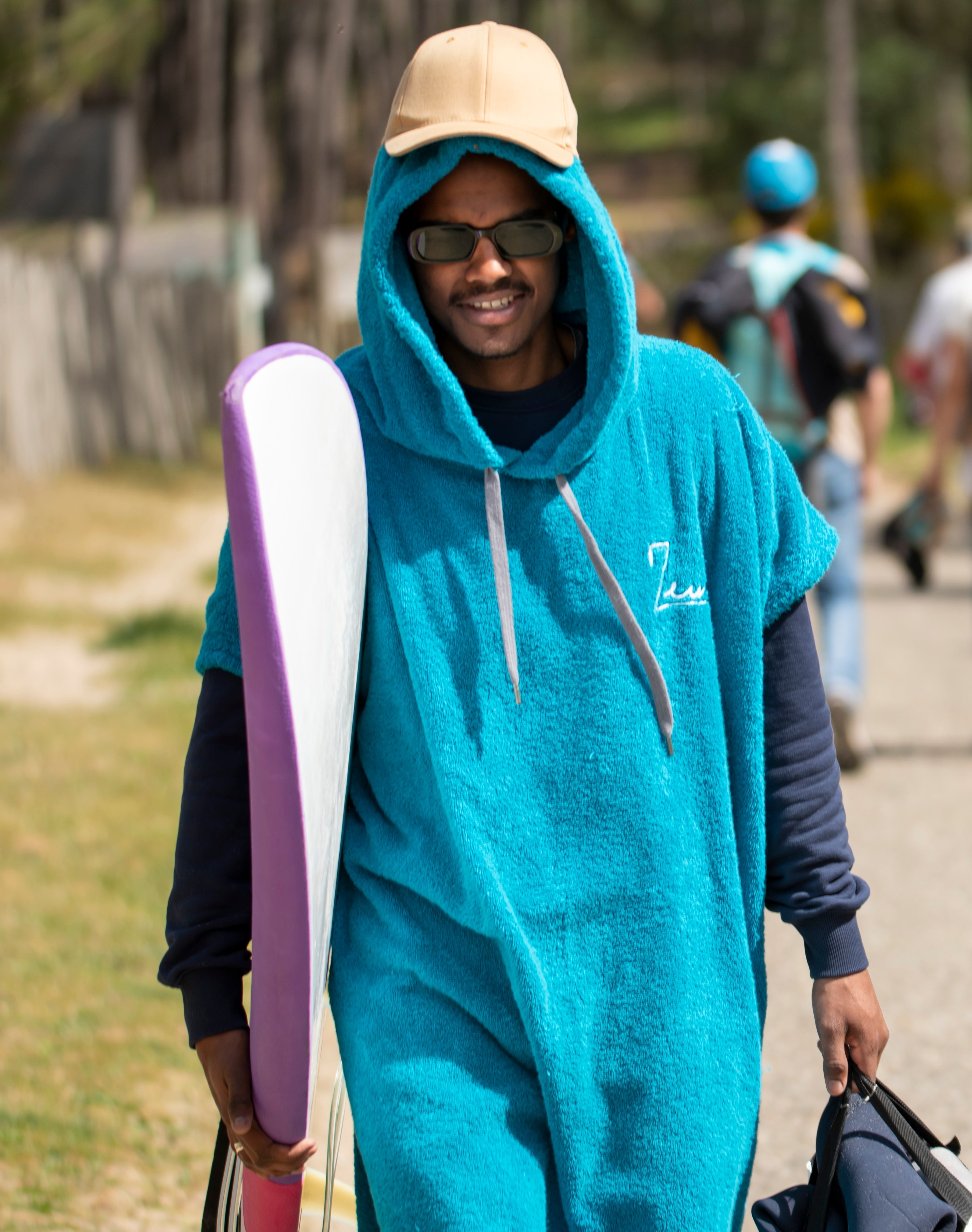 a man in a blue towel holding a surfboard