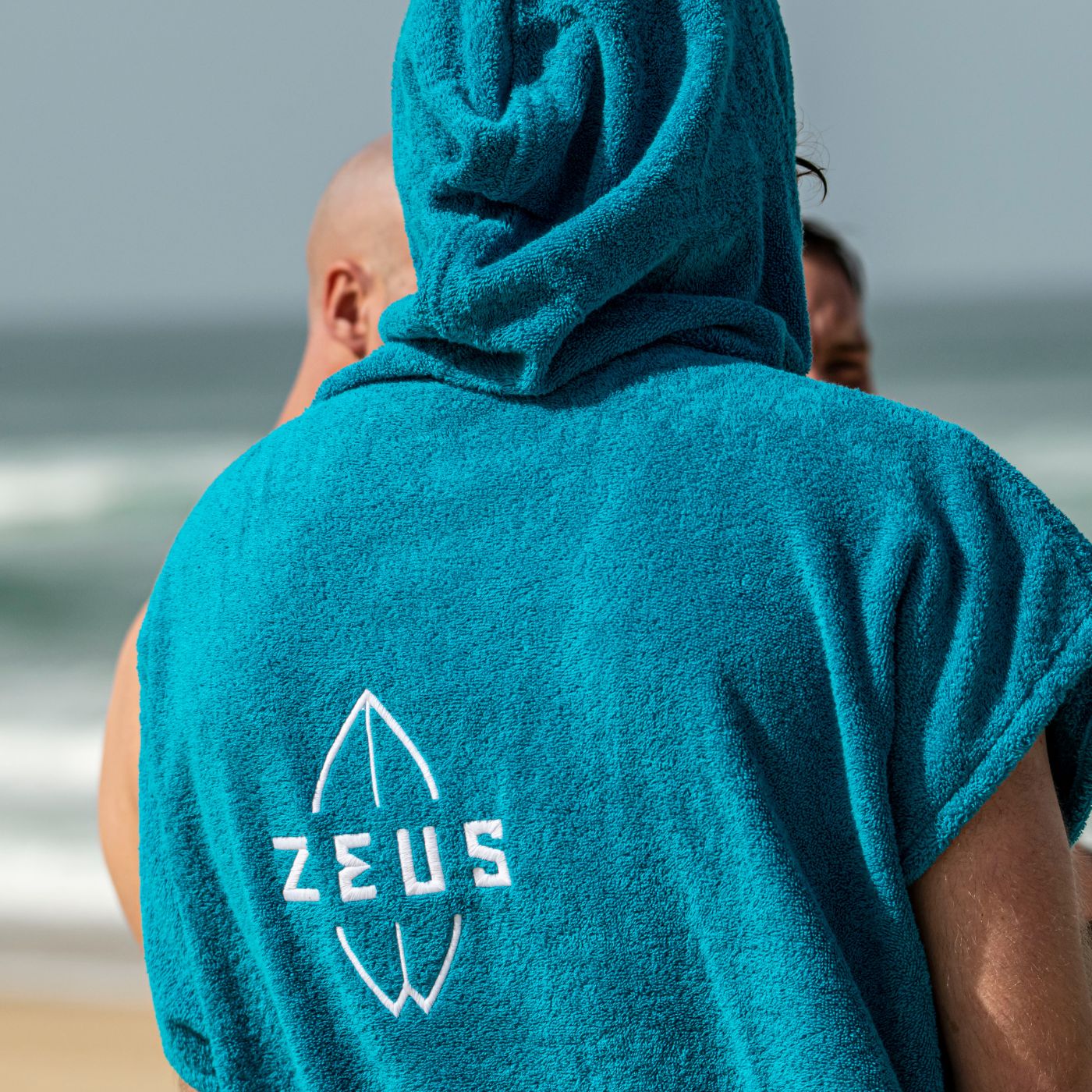 a man in a blue towel standing on the beach