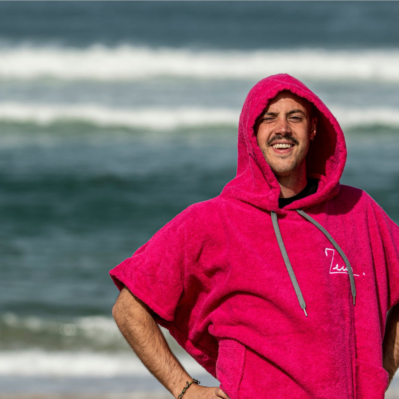 a man in a pink towel standing on the beach